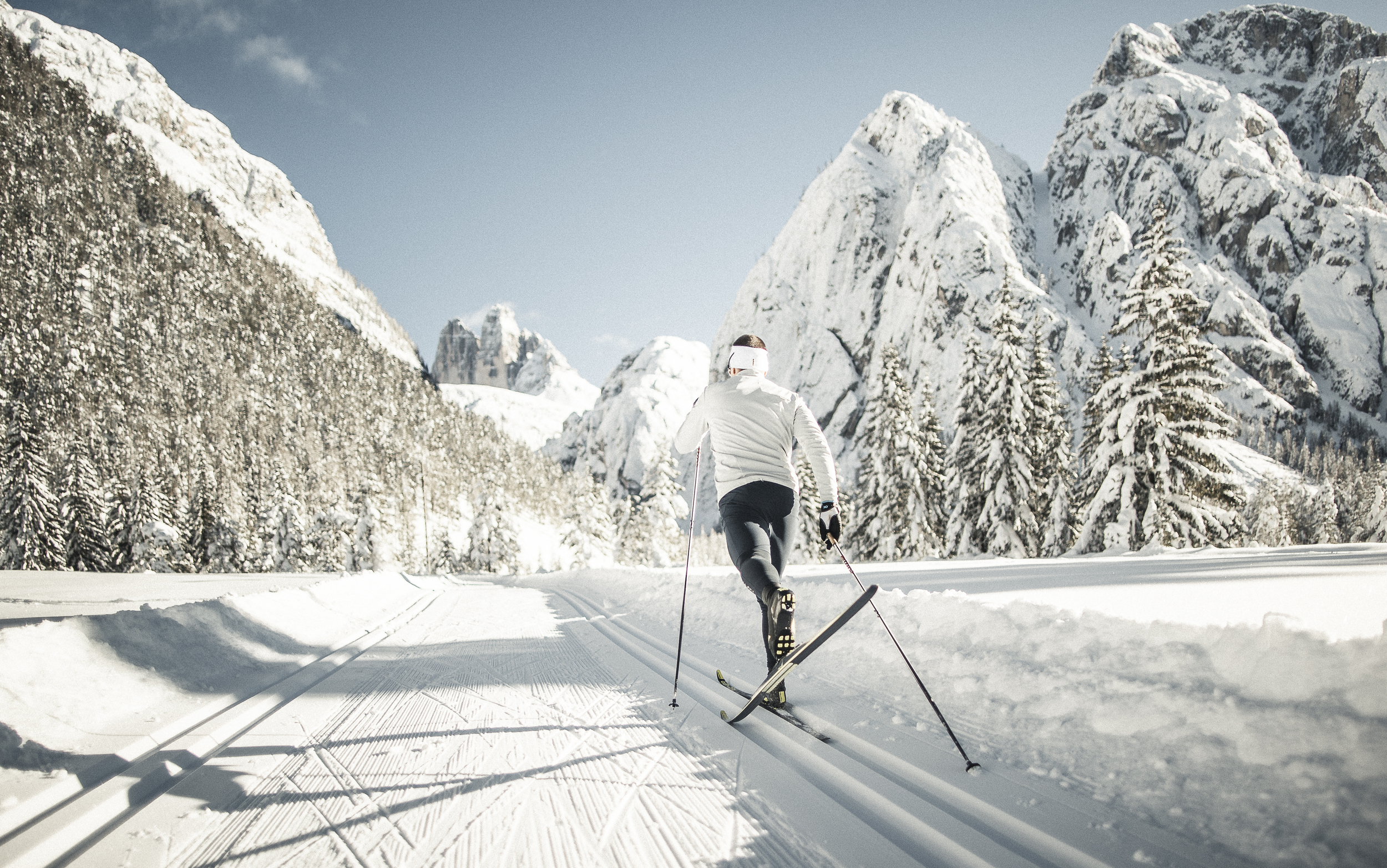 A cross-country skier glides along a groomed trail using the classic style