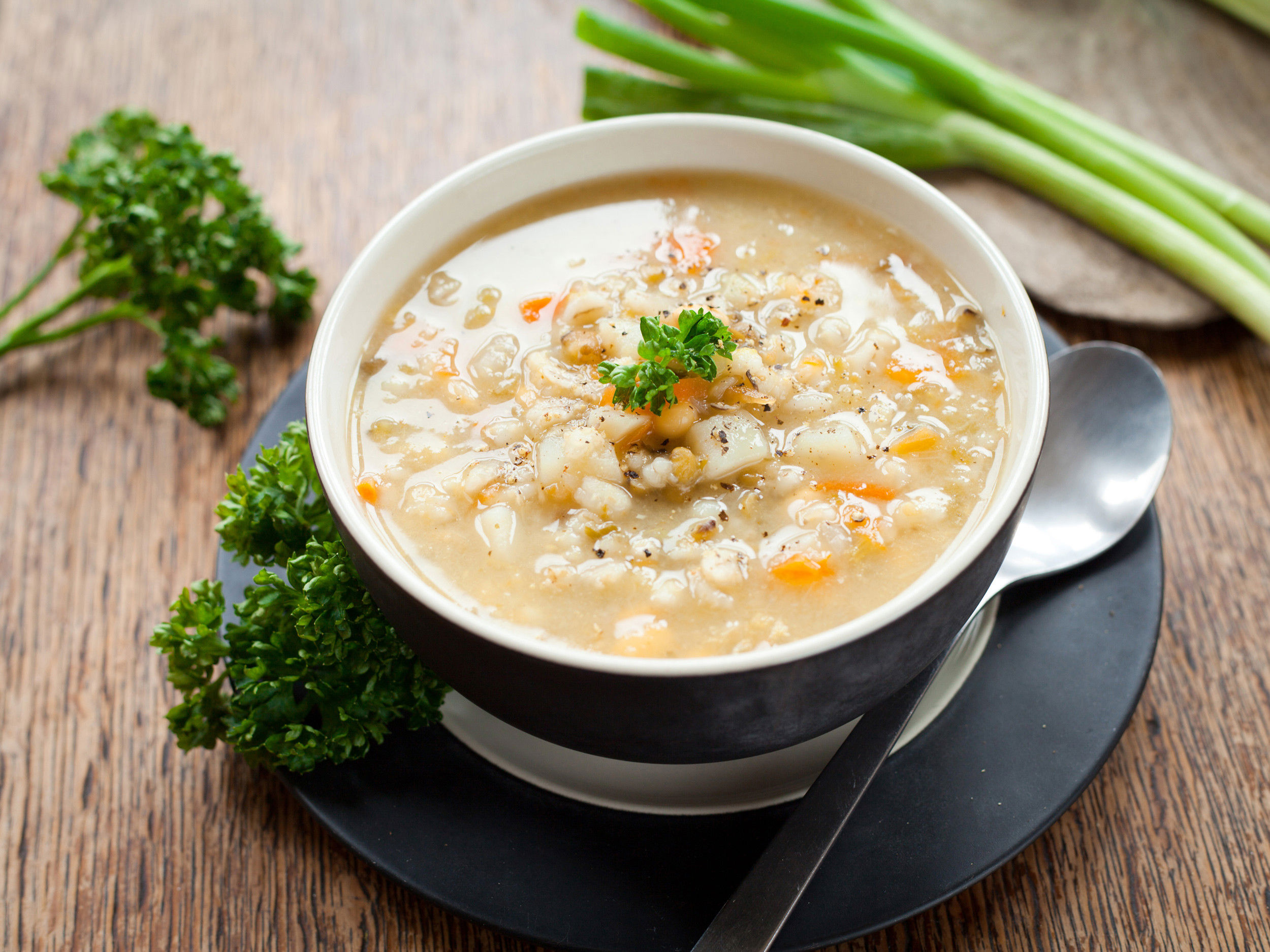 Plate of barley soup decorated with vegetables.