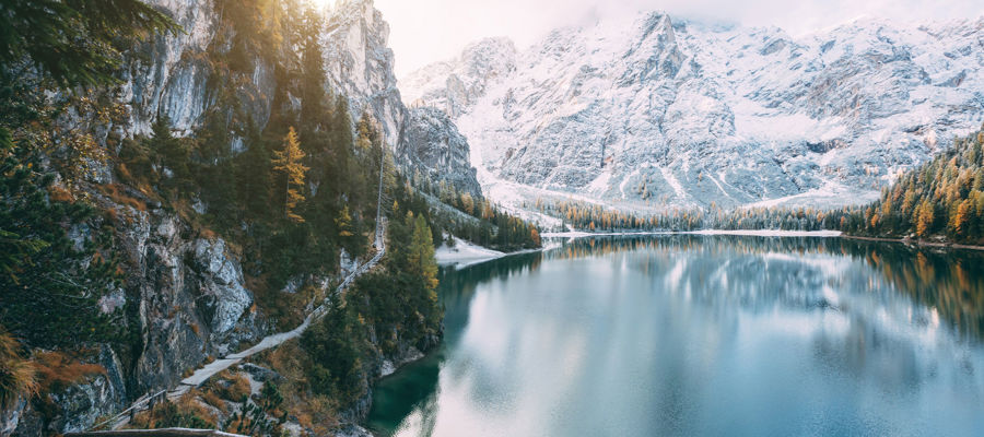 Nature in South Tyrol: Deep blue mountain lake, surrounded by snow-covered mountains and forests