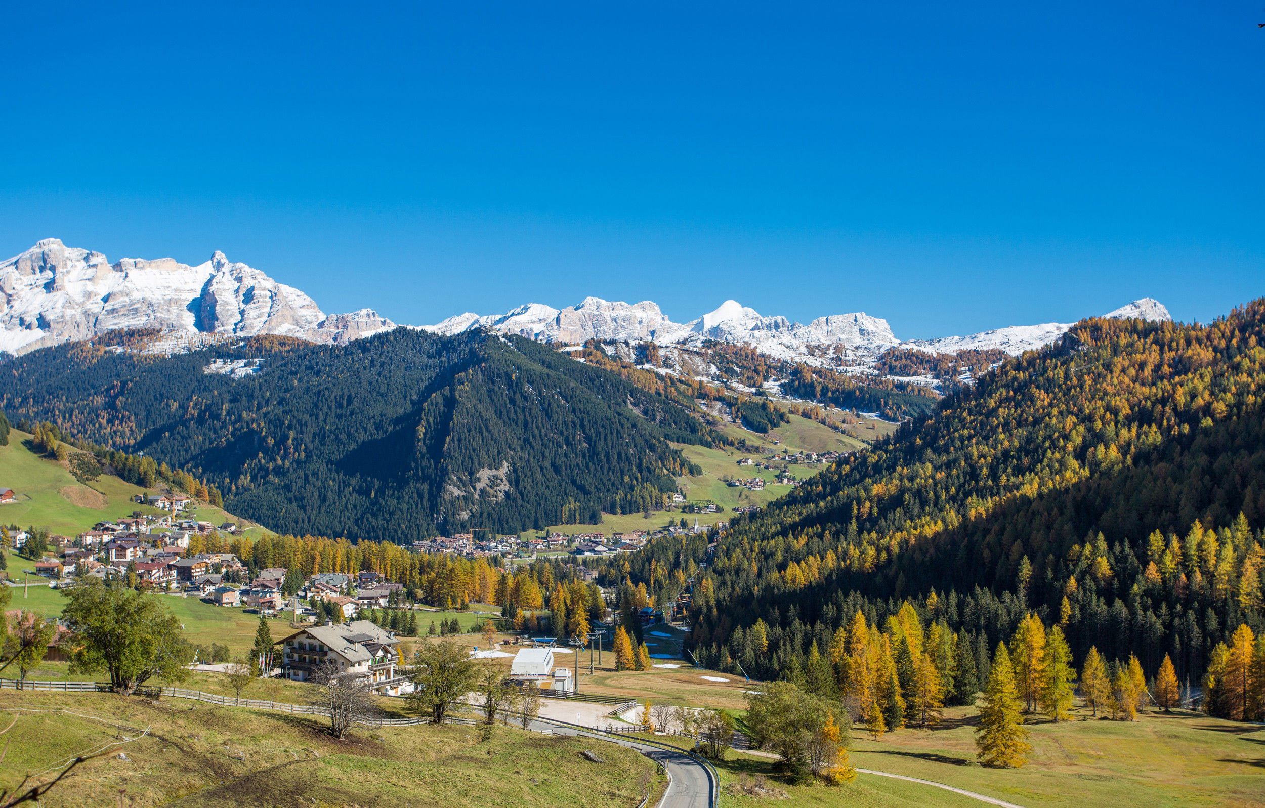 View towards Kolfuschg in bright autumn weather with snow-covered Dolomites