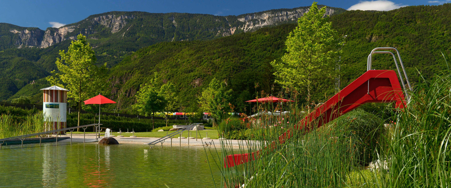 Gargazon Natural Bath Lake with red slide and sunbathing lawn.