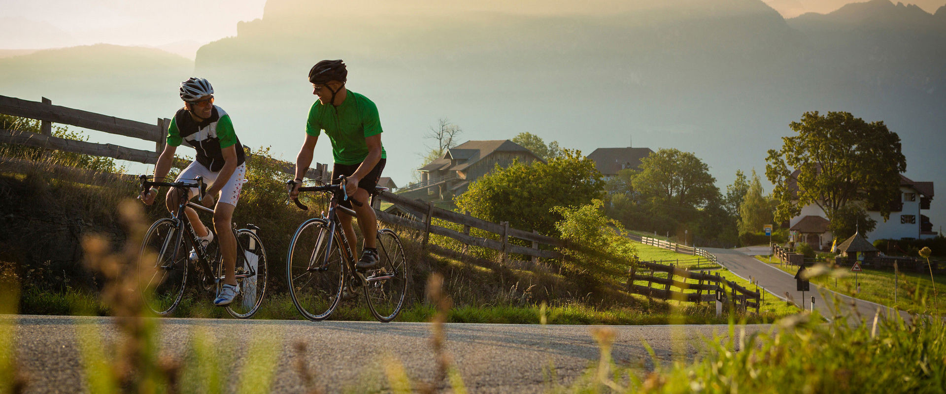 Cycling in the mountains. Two cyclists ride up the hill on the road.