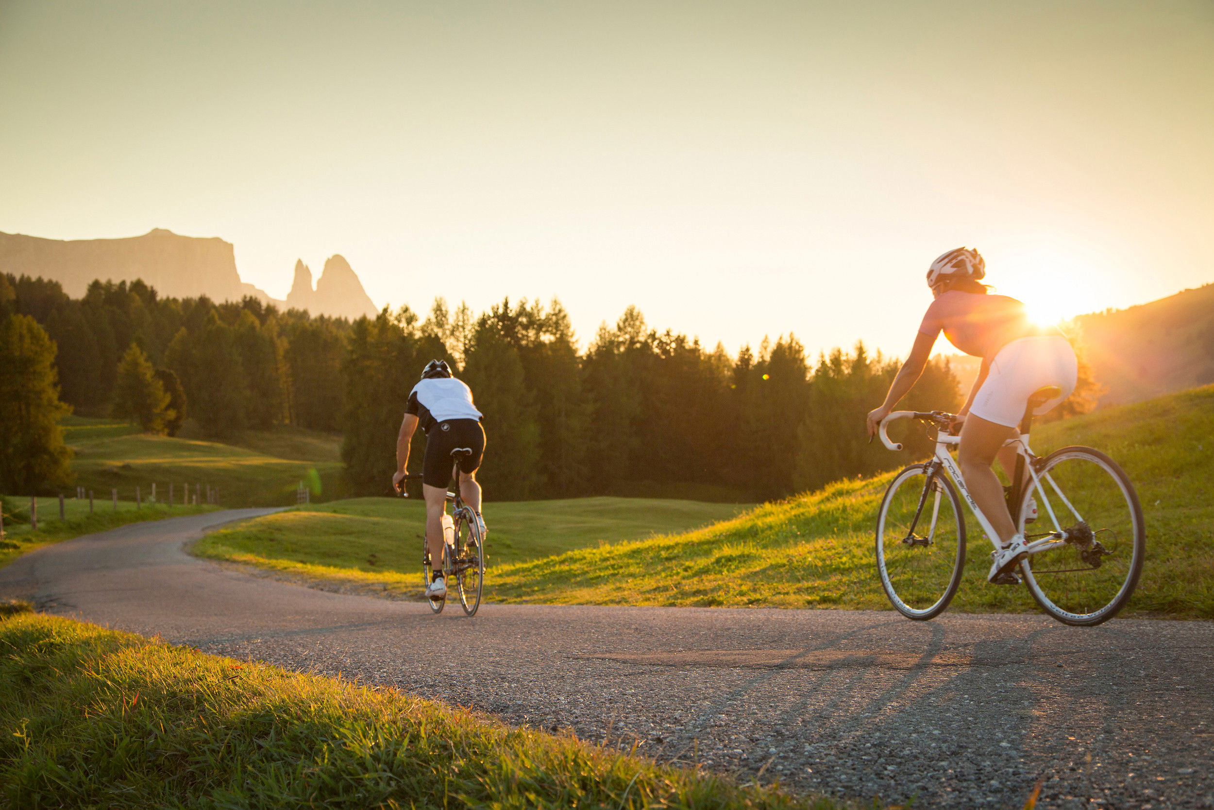 2 cyclists ride down the mountain during a breathtaking sunset. 