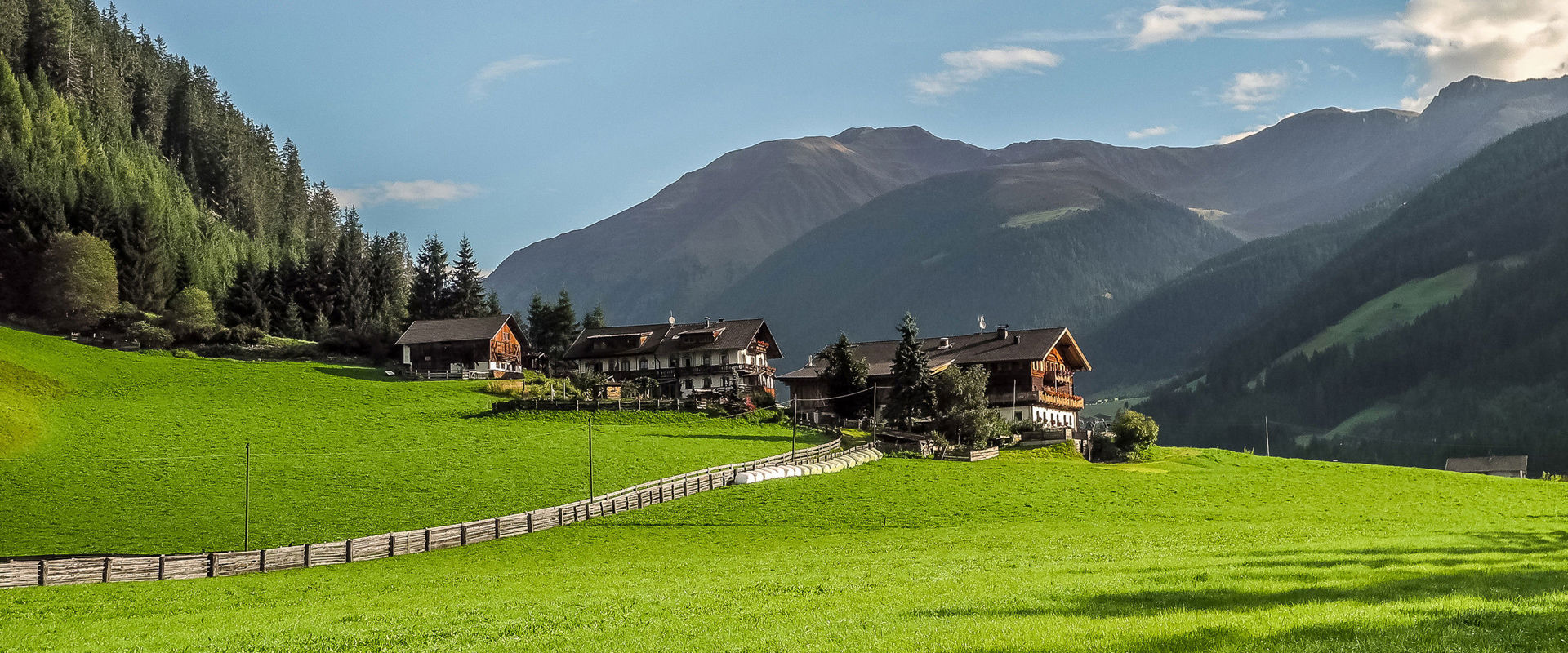 Holiday in Gsies. Three farmhouses in the midst of green meadows and mountain slopes.