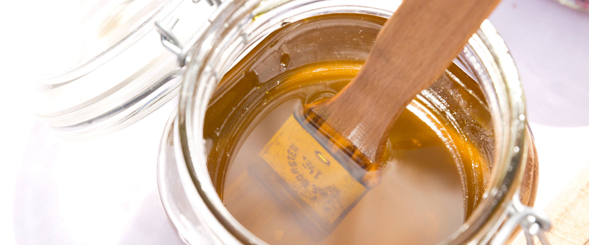 Glass jar with honey and brush.