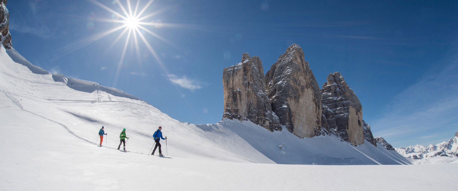 Three Peaks in winter Snow-covered winter landscape around the Three Peaks. Below the mountain 3 people pass with their ski.
