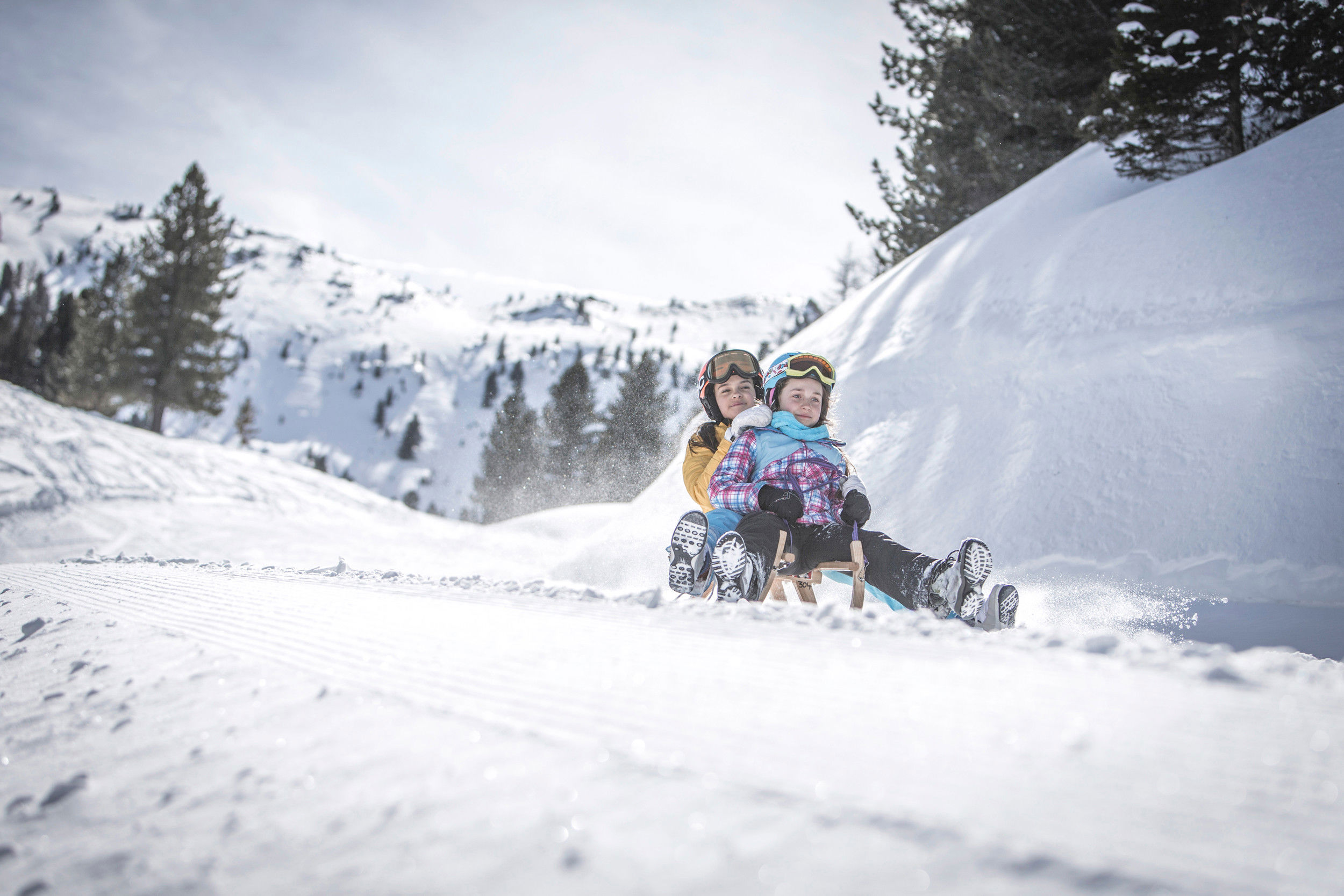 Mother and daughter ride down the slope on a toboggan.