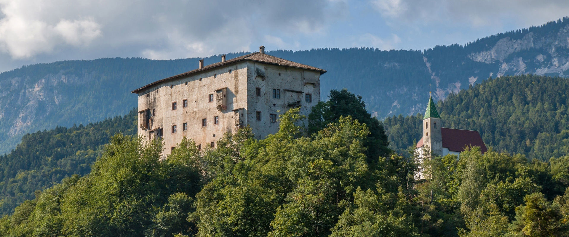 Katzenzungen Castle in Prissian. Castle on a wooded hill with a church next to it.
