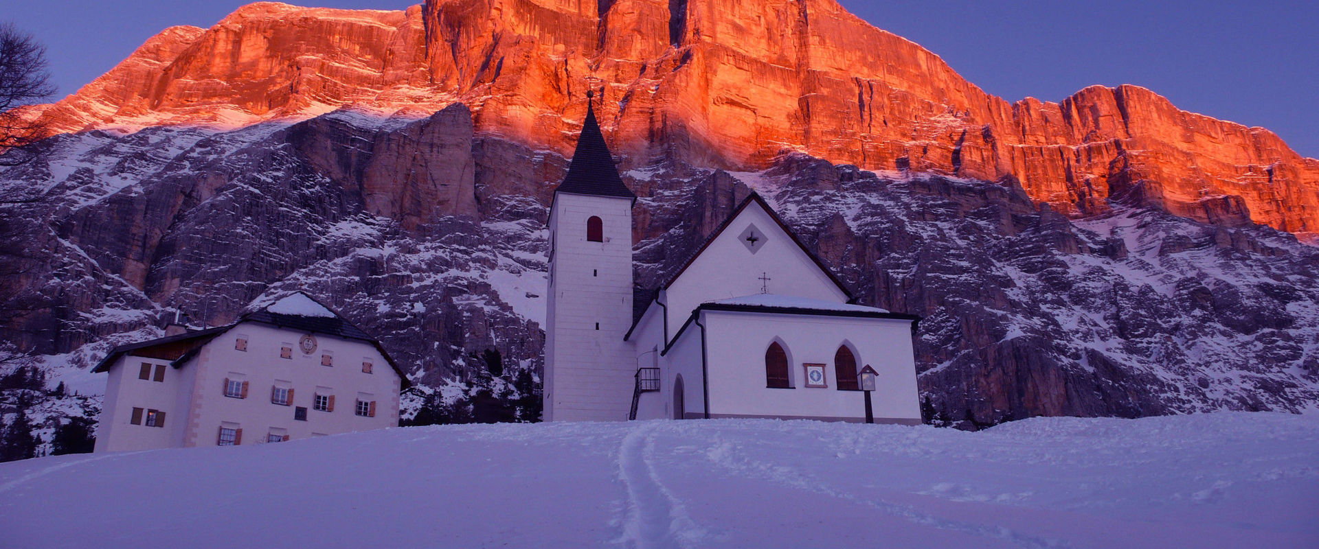 Pedratsches Pilgrimage Church Hl. Kreuz at sunset with the Dolomites glowing red