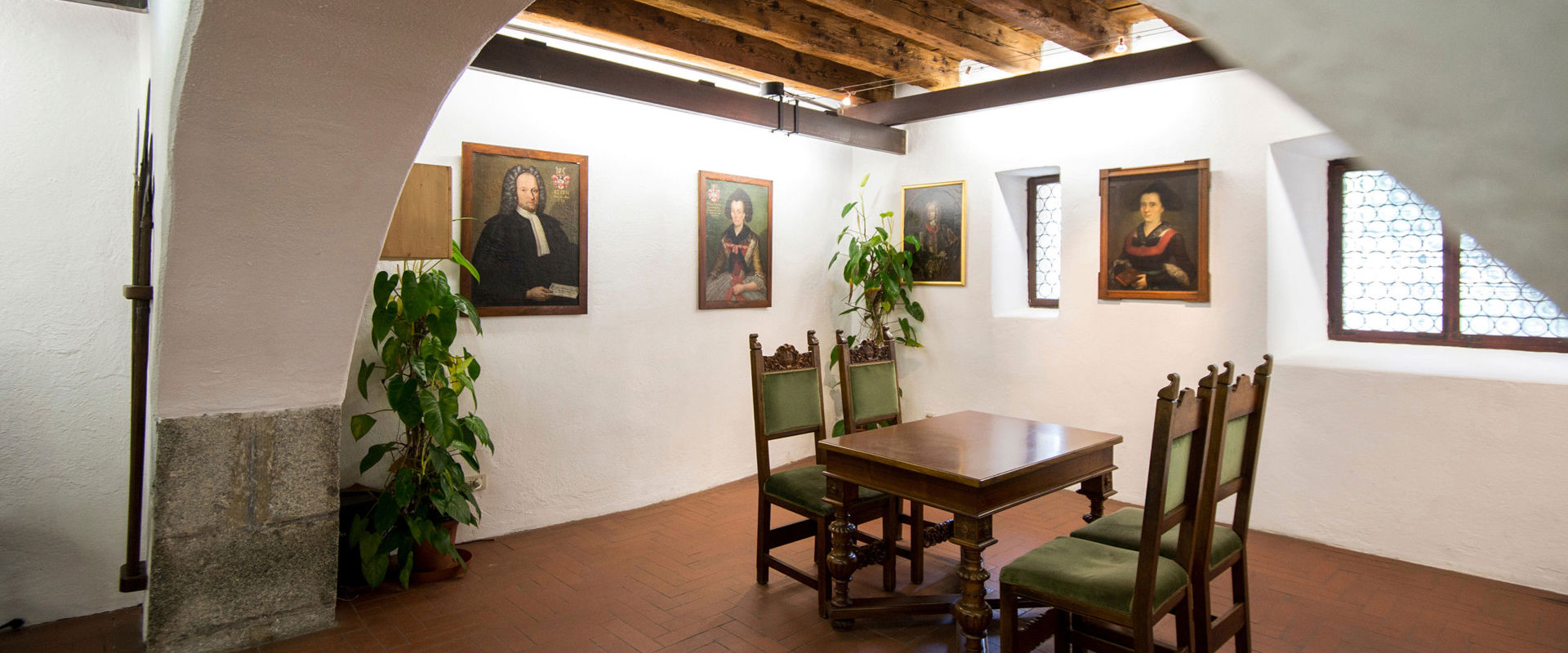 Prince's Castle Meran Room with old wooden table and portraits of noble princes and dukes.