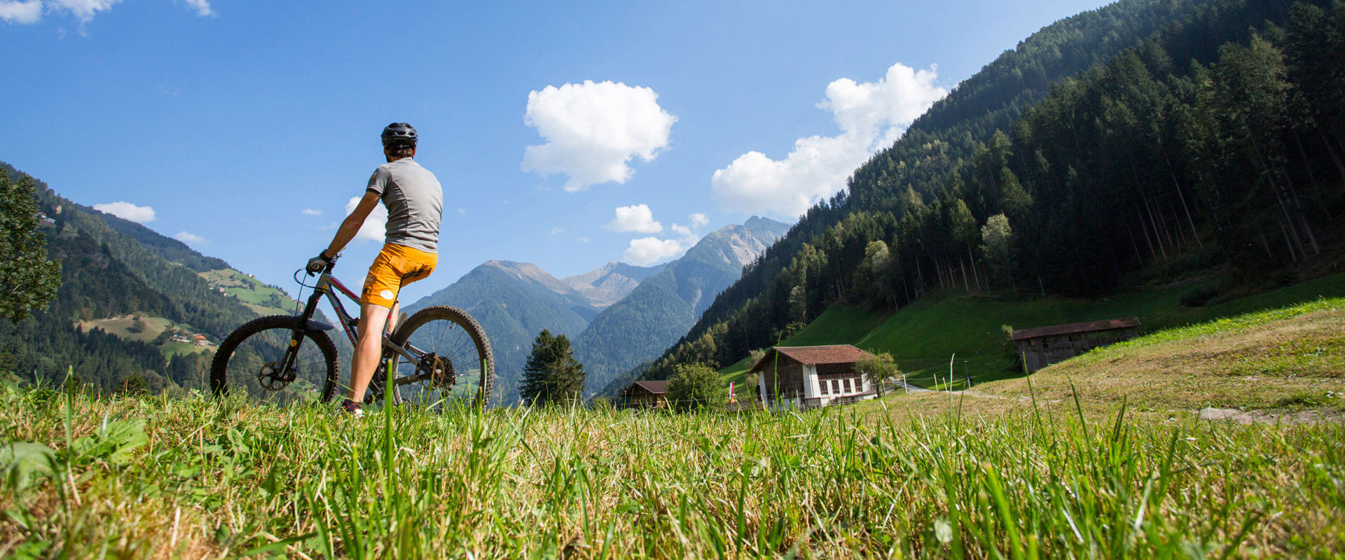 By bike on the mountain. A man sits on a bicycle and looks into the distance at the mountain peaks.