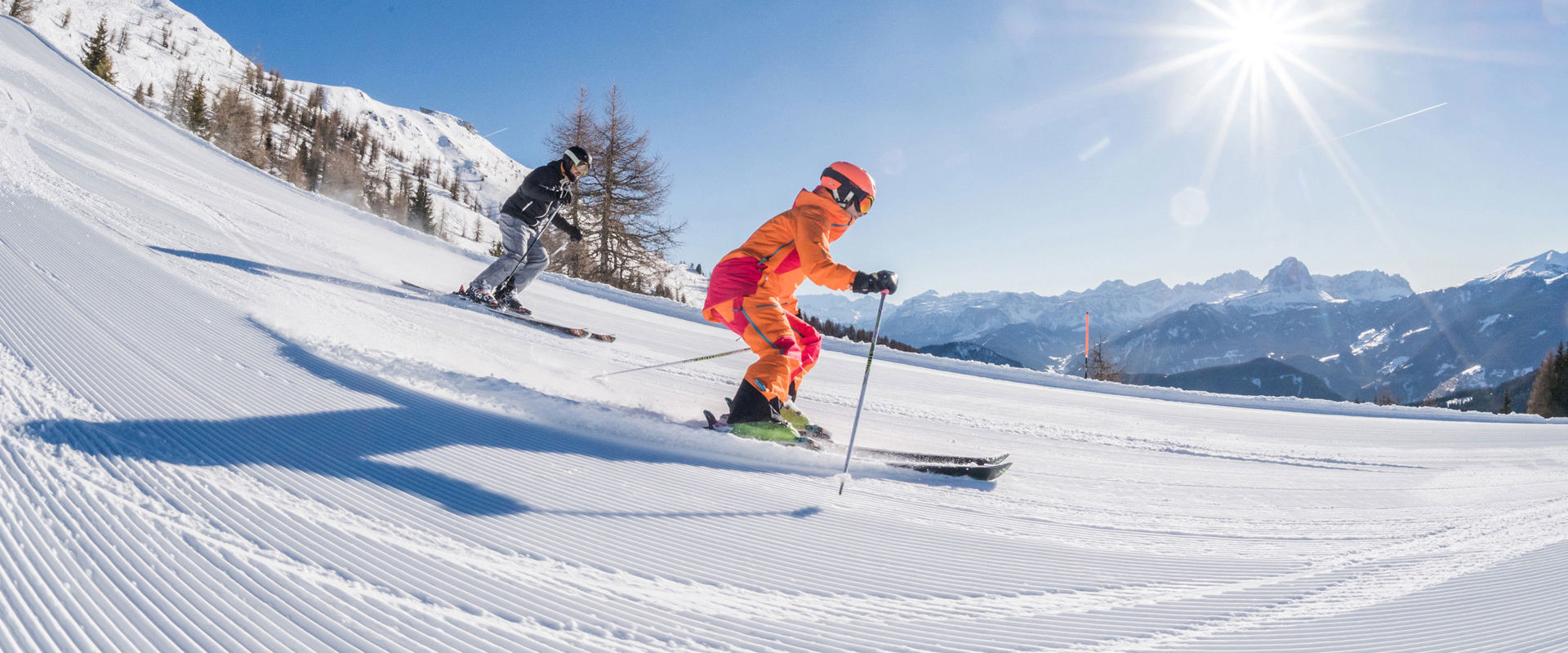Freshly prepared ski slope 2 skiers ride down the freshly groomed slope.