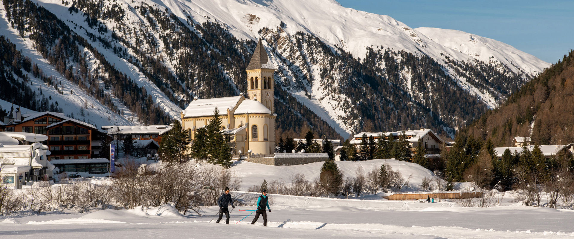 Sulden in winter. Two cross-country skiers on the trail right next to the village of Sulden.