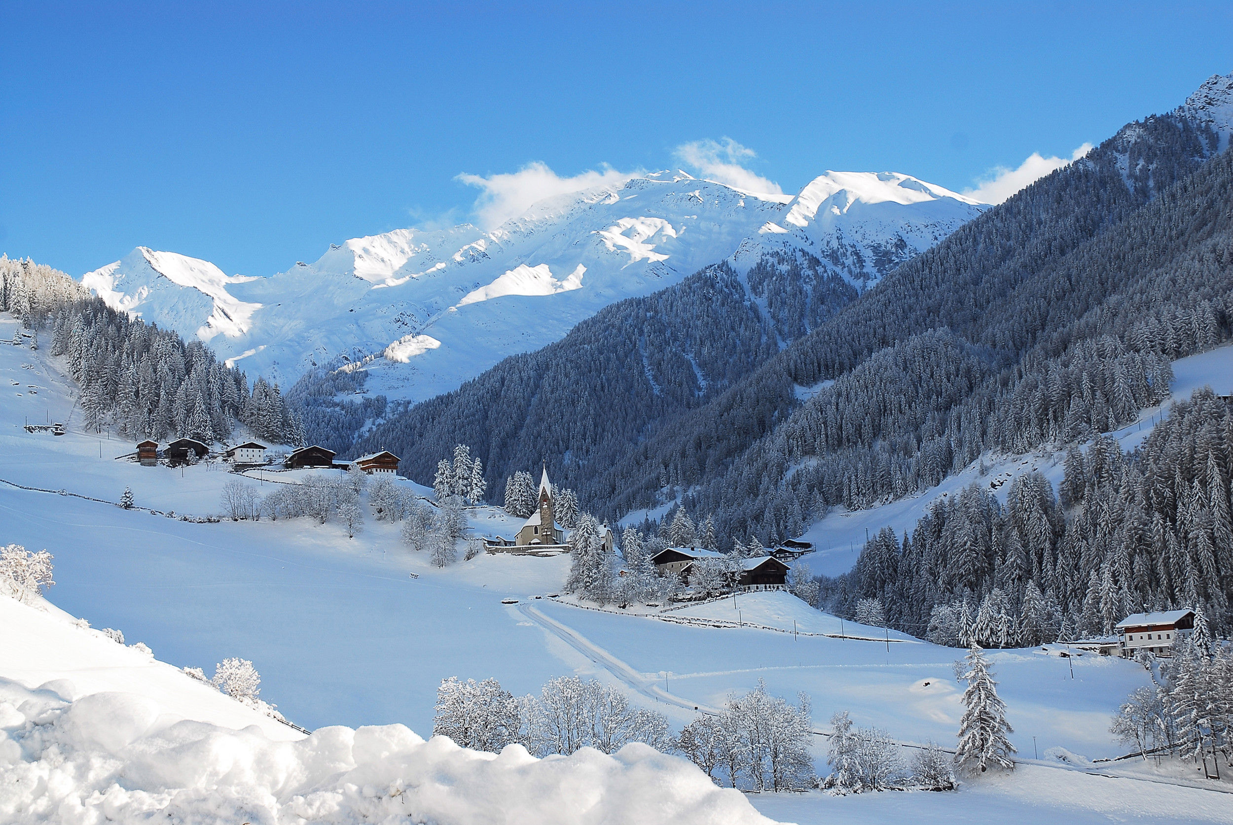 View of some houses in St. Peter in the Ahrntal Valley with surrounding snowy landscape