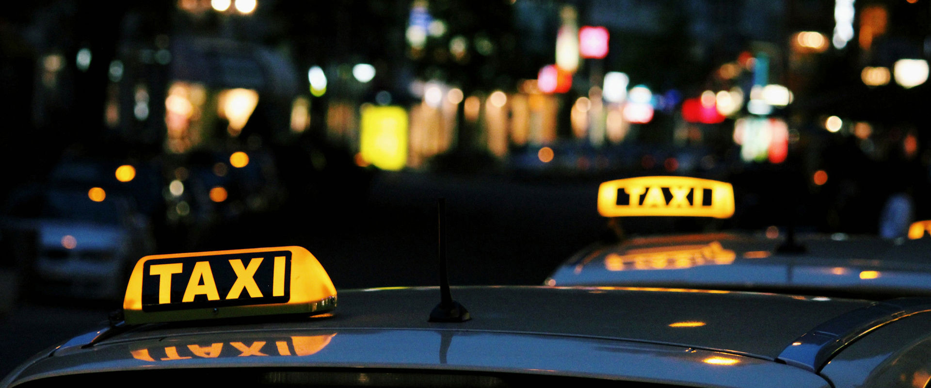 Cabs City at night with stationary taxis a, roadside.
