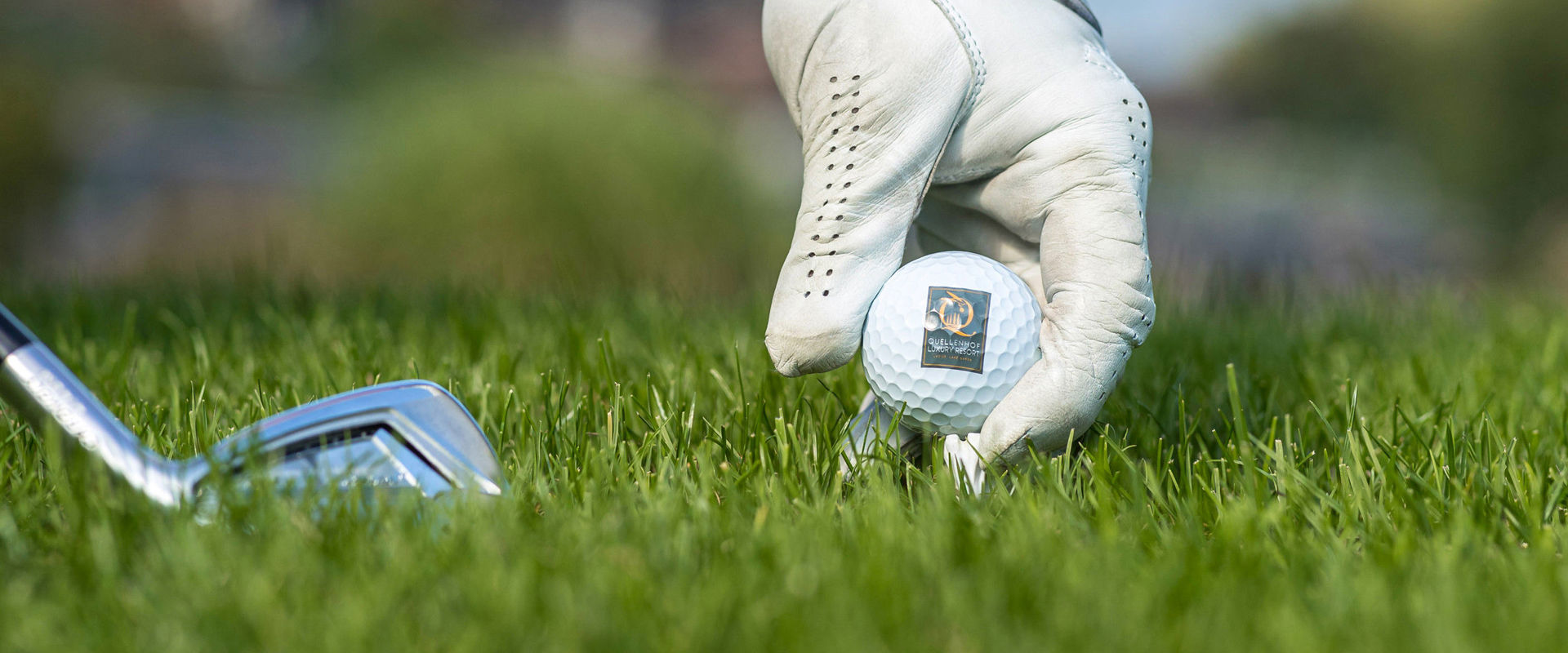 Golf course Quellenhof Hand places the golf ball on the grass for the tee shot.