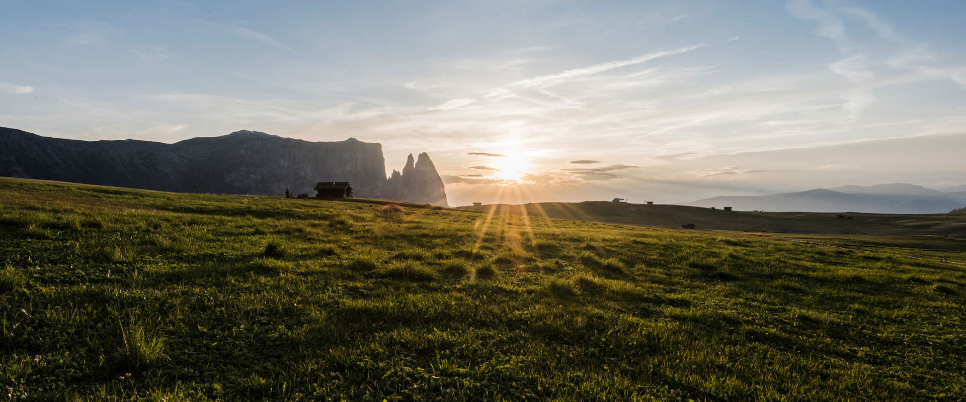 Schlern Green meadow of the Seiser plateau and sunset behind the Schlen.