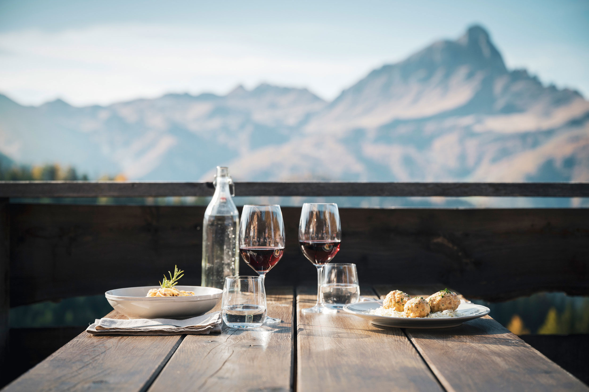 2 plates and wine glasses on a wooden table.
