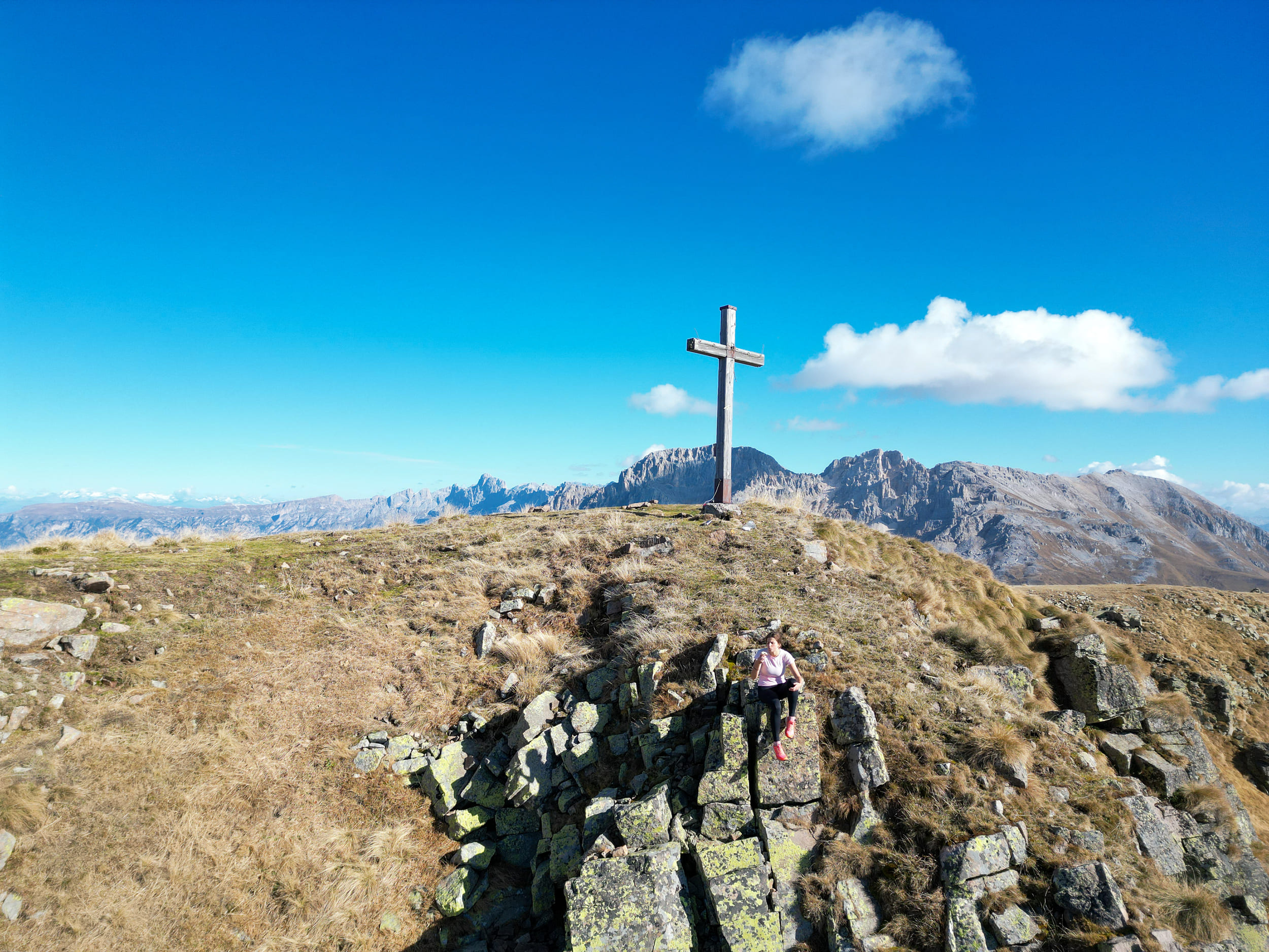 Hiker at the summit cross on a mountain peak