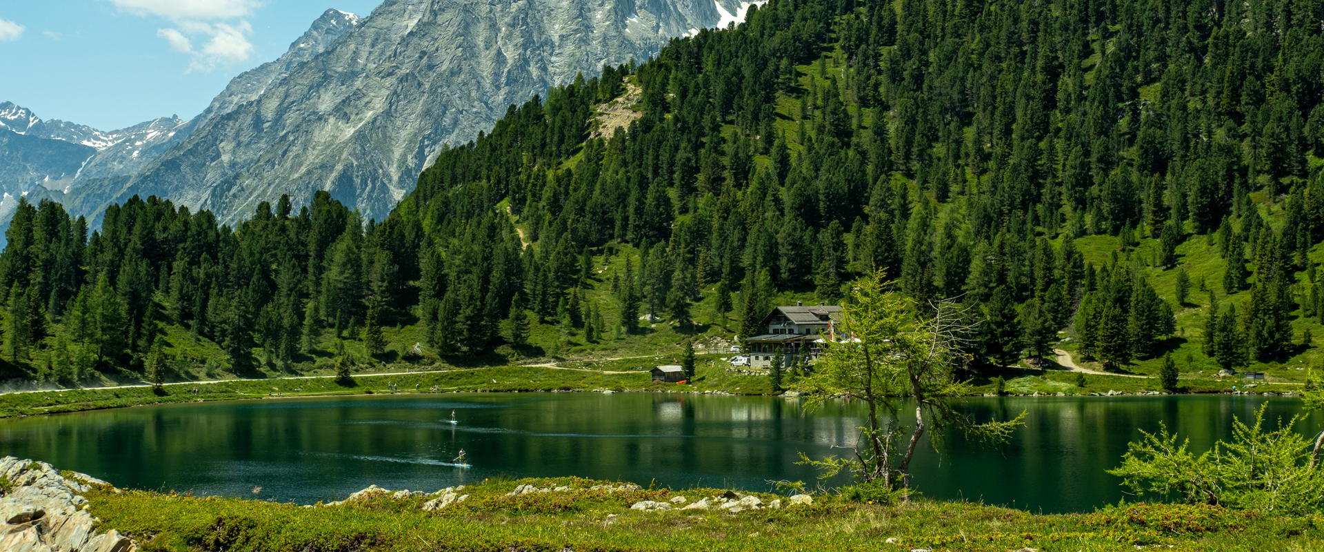 Obersee Mountain lake in front of alpine hut, forest and mountain peaks on the Staller Sattel