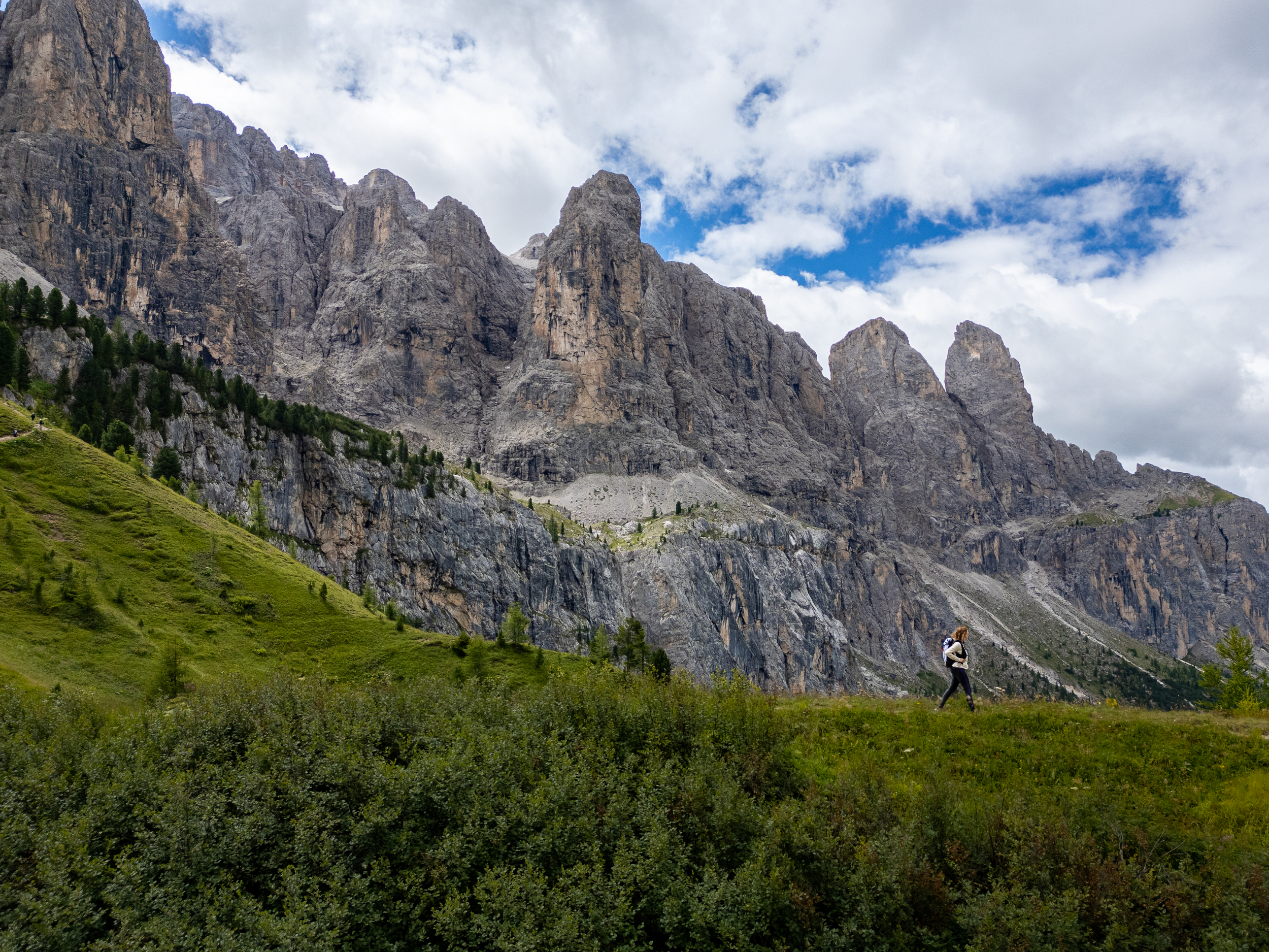 Hiker on a mountain meadow with rock faces in the background