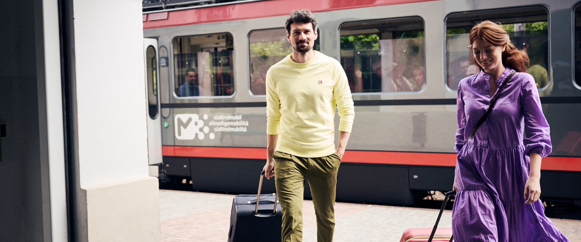 Travel by train in South Tyrol Couple with suitcases at the railway station, with train in the background
