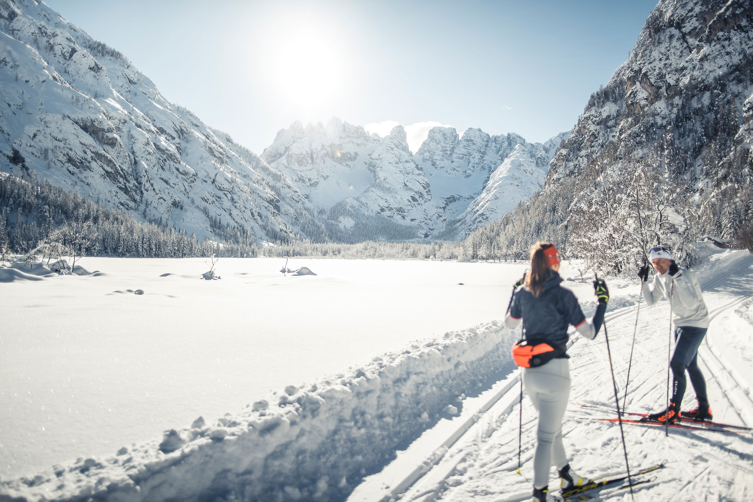 Two women ski on the cross-country trail around the snow-covered lake.