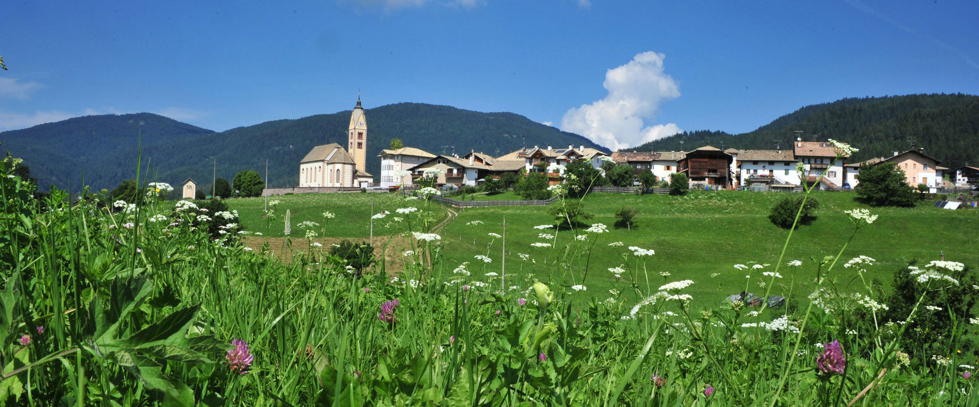 Altrei The village of Altrei surrounded by lush green meadows and a dreamlike mountain landscape.